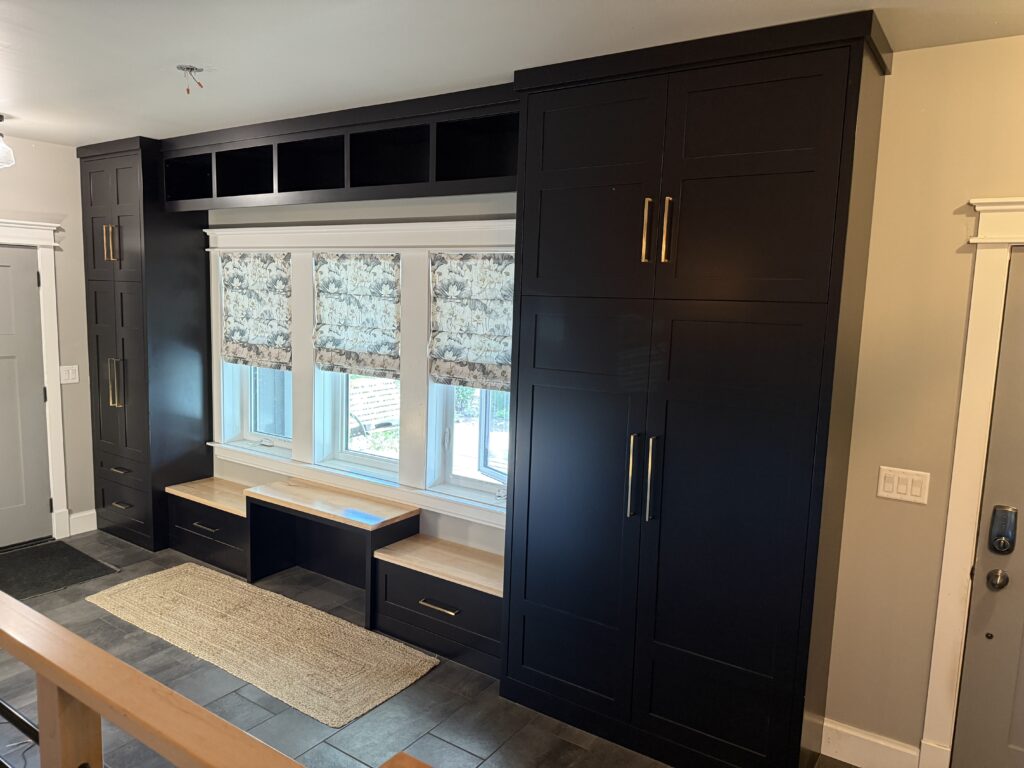 Full height mudroom cabinets with window seat bench, finished in tricorn black with champagne bronze hardware 