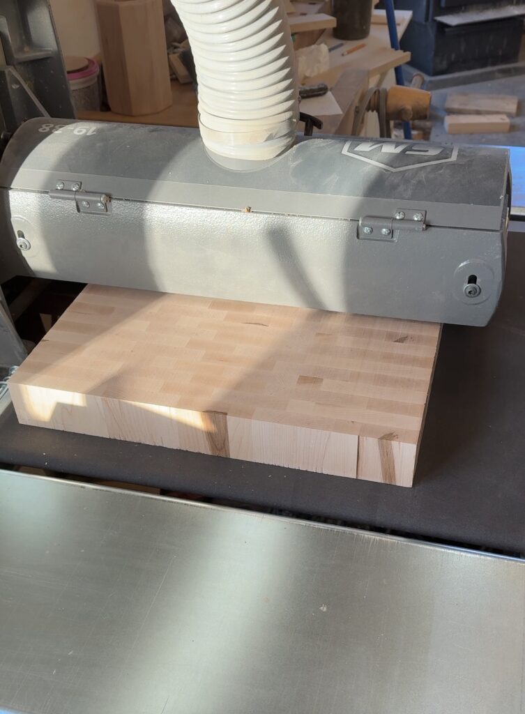 End grain cutting board being run through a drum sander.